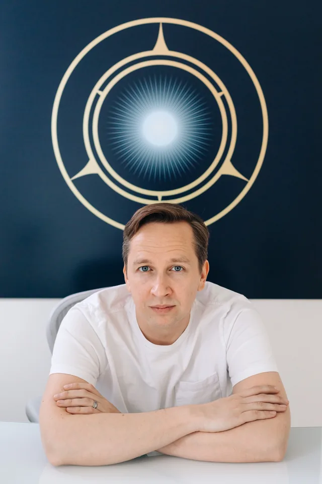 Arkady Kulik, seated in front of a blue and gold artwork.